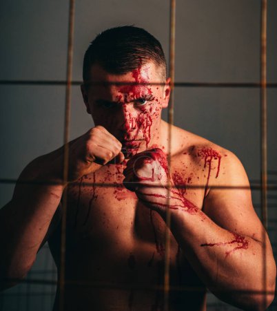 Photo for Psychic disease. Murderer brutal aggressive guy. Fight and attack. Aggressive person. Strong aggressive monster behind grid. Bodybuilder nude torso soiled blood. Prison for monster. Psycho mad man. - Royalty Free Image