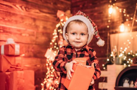 Foto de Niño feliz con caja de regalo de Navidad. Sorpresa. Caja de regalo. Un niño pequeño en ropa abrigada.Feliz Navidad y feliz año nuevo - Imagen libre de derechos