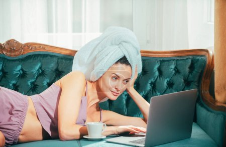 Photo for Distance online working from bed. Young attractive woman with coffee and laptop relaxing at home. Cozy lazy mornig. Beautiful girl online chatting in the mornig on bed - Royalty Free Image