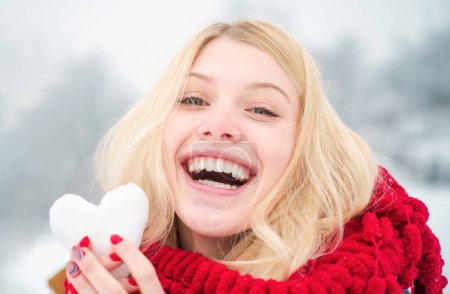 Téléchargez les photos : Fille en mitaines tenir boule de neige. Portrait d'une femme heureuse en hiver. Fille gaie à l'extérieur. Mignon ludique jeune femme en plein air profiter de la première neige - en image libre de droit