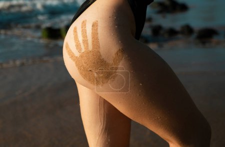 Téléchargez les photos : Gros plan dos sexy d'une belle femme en maillot de bain en mer. Corps bronzé sexy, silhouette parfaite. Repos sur une plage tropicale. Fesses féminines - en image libre de droit