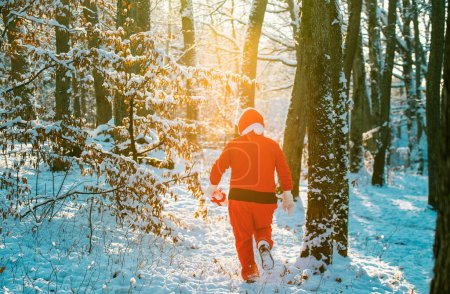 Foto de Santa Claus en traje rojo caminar en el bosque de invierno. Entrega regalos de Navidad. Feliz año nuevo. Feliz Navidad y Feliz Año Nuevo - Imagen libre de derechos