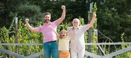 Foto de Familia emocionada junto con tres generaciones diferentes edades abuelo padre e hijo sorprendido en el jardín de primavera - Imagen libre de derechos