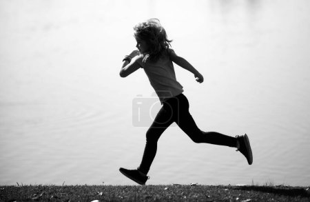 Foto de Niño trotando en el parque al aire libre. Deportes para niños, felices niños activos corriendo al aire libre, corriendo en el parque de primavera. Deportes al aire libre y fitness para niños, ejercicio al aire libre - Imagen libre de derechos