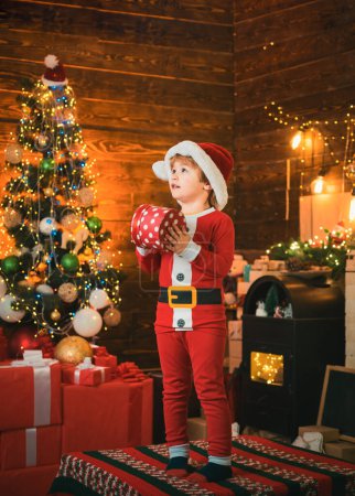 Photo for Bright New Years interior. Boy cute child cheerful mood play near Christmas tree. Indoor. Joy and happiness. Christmas shopping concept. Holidays and winter childhood concept - Royalty Free Image