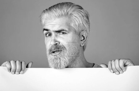 Foto de Hombre sosteniendo retrato de estudio de cartón en blanco. En blanco, papel vacío, cartelera con espacio de copia para el texto - Imagen libre de derechos