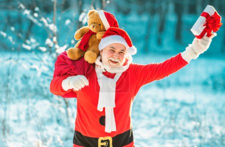 Foto de Feliz Navidad y Feliz Año Nuevo concepto. Santa Claus tirando de una enorme bolsa de regalos sobre fondo blanco de la naturaleza - Imagen libre de derechos