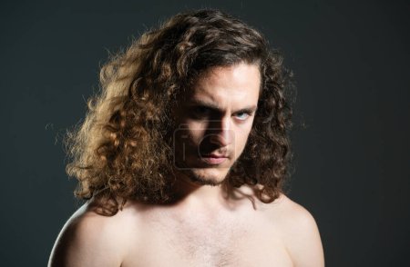 Téléchargez les photos : Portrait de beau mec sexy aux cheveux bouclés. Macho brutal gars avec longue bouclée isolé sur fond gris - en image libre de droit