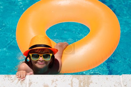 Téléchargez les photos : Les enfants adorent l'été. Enfant garçon 7, 8, 9 ans nager sur anneau flottant dans la piscine. Enfants été drôle visage - en image libre de droit