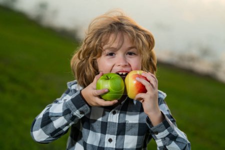 Photo for Kid dressed casual holding and apple with a smile and showing eats healthy food - Royalty Free Image