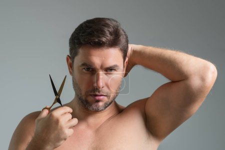 Téléchargez les photos : Blanc bel homme confiant essayant de faire une coupe de cheveux par lui-même avec des ciseaux. Une coupe masculine. Ciseaux de coiffeur, salon de coiffure. Ciseaux de coiffeur. Concept de coupe de cheveux. Hommes coiffure et coupe de cheveux - en image libre de droit