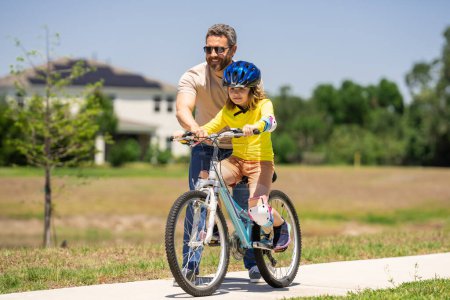 Photo for Happy Fathers day. Father and son on the bicycle. Father and son riding a bike in summer park. Kid learning to riding bicycle. Father and son riding bikes wearing helmets. Child on bicycle outdoor - Royalty Free Image
