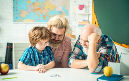 Photo for Grandfather and father teaching son. Granddad and cute little boy grandson study and learn together, playing games. Senior grandpa and middle aged dad play with grandchild son - Royalty Free Image