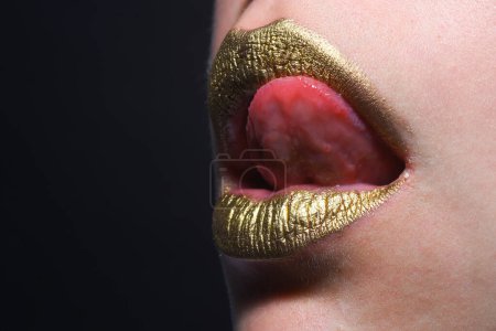 Photo for Sexy tongue licking lips. Golden lips. Luxury gold lips make-up. Golden lips with creative metallic lipstick. Gold metal lip. Sensual woman mouth, clse up, macro - Royalty Free Image