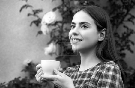 Téléchargez les photos : Portrait de jolie jeune femme dans le parc avec tasse de café pendant la journée d'été. Femme romantique avec tasse de café - en image libre de droit