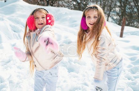 Photo for Snowball fight. Winter kids having fun playing in snow. Kids throwing a snowball. Two little girl playing on snow in winter time - Royalty Free Image