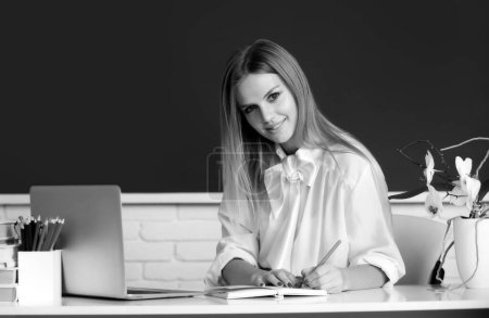 Photo for Portrait of smiling young college student writing, studying in classroom - Royalty Free Image