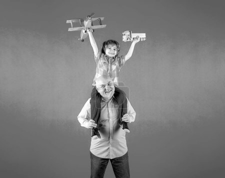 Photo for Grandfather and grandson piggyback ride with plane and wooden toy truck. Men generation granddad and grandchild - Royalty Free Image
