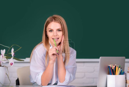 Photo for Portrait of young female college student studying in classroom on class with blackboard background on school interior, college classroom, class in university - Royalty Free Image