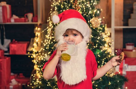 Photo for Santa kids picking cookie. Santa fun. Santa Claus takes a cookie on Christmas Eve as a thank you gift for leaving presents. Portrait of little Santa child holding chocolate cookie and glass of milk - Royalty Free Image