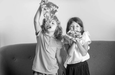 Téléchargez les photos : Pizza and kids, slices pizza in kids hand. Children eating tasty fast food pizza with cheese. Happy time for hungry friends. Funny kids little girl and boy eating tasty pizza - en image libre de droit