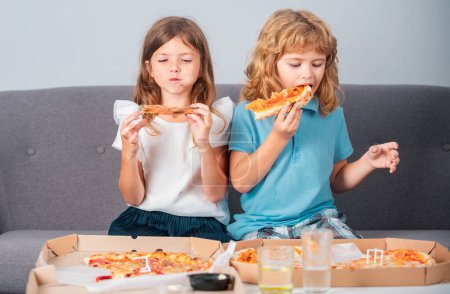 Foto de Niña y niño comen pizza. Niños hambrientos comiendo pizza. Comida rápida poco saludable - Imagen libre de derechos