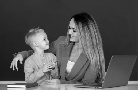 Photo for Mother and son together using computer laptop. School child learning education online lesson. Teacher helps school kids to learn lesson - Royalty Free Image