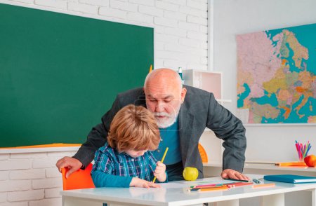 Photo for Teacher with male elementary school pupil with problem. Pupil and Teacher in classroom - Royalty Free Image