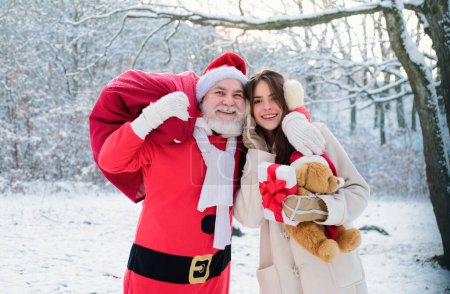 Photo for Santa grandfather and daughter helper girl deliver Christmas gifts in snowy winter mountain. New Year and xmas is coming - Royalty Free Image