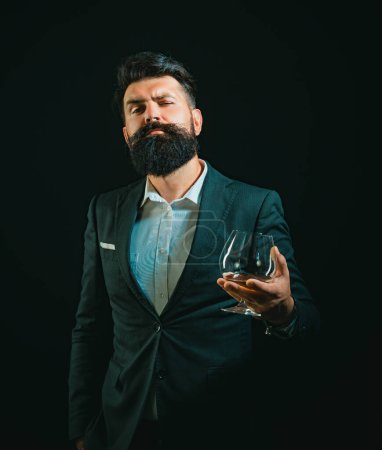 Photo for Man or businessman drinks cognac on black background. Degustation and tasting. Man with beard holds glass of brandy - Royalty Free Image