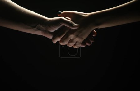 Téléchargez les photos : Une poignée de main entre les deux partenaires. Sauvetage ou geste d'aide des mains. Concept de salut. Mains de deux personnes au moment du sauvetage, accord, aide. Isolé sur fond noir - en image libre de droit