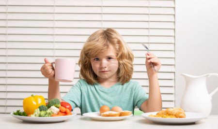 Téléchargez les photos : Petit garçon petit déjeuner sain. Nutrition et développement des enfants. Manger des légumes par enfant les rend plus sains - en image libre de droit
