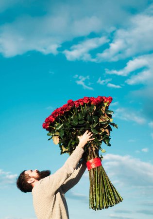 Foto de Hombre novio con ramo de rosas. Concepto de regalos del día de San Valentín. Guapo chico dando flores a novia - Imagen libre de derechos