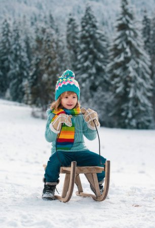 Photo for Child boy sledding in winter. Kid riding on snow slides in winter. Wonderful Christmas scene - Royalty Free Image