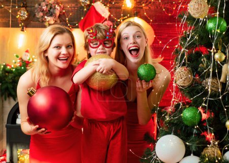 Photo for Christmas party. Women red dresses festive mood celebrate christmas with little cute baby. Family bonds. Love peace joy wishes. Kid boy with mom or aunts sisters having fun. Christmas family fun. - Royalty Free Image