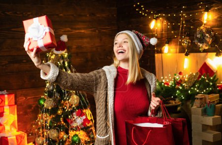 Photo for Christmas girl is looking at the Christmas gift in her hand. New year concept. Happy woman. Beauty Christmas fashion model girl holding Christmas gift - Royalty Free Image