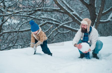 Téléchargez les photos : Joyeux Noël et bonne année. Père et fils jouent en vêtements d'hiver. Famille d'hiver dans le parc d'hiver givré - en image libre de droit