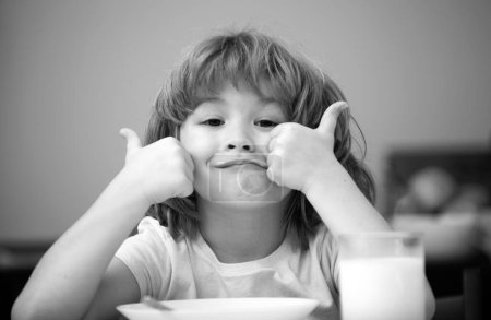 Foto de Retrato de un niño lindo comiendo sopa o desayunando almorzando junto a la mesa en casa con cuchara. Nutrición infantil. Alimentos saludables para niños - Imagen libre de derechos
