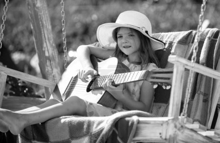 Foto de Feliz niña sonriente tocar la guitarra. Actividad de verano para niños en climas cálidos. Feliz linda chica adolescente balanceo y divertirse saludable actividad de vacaciones de verano - Imagen libre de derechos