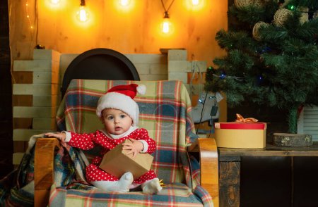 Foto de Niño con un regalo de Navidad sobre fondo de madera. Niños de Navidad. Lindo niño está decorando el árbol de Navidad en el interior. Niños felices - Imagen libre de derechos