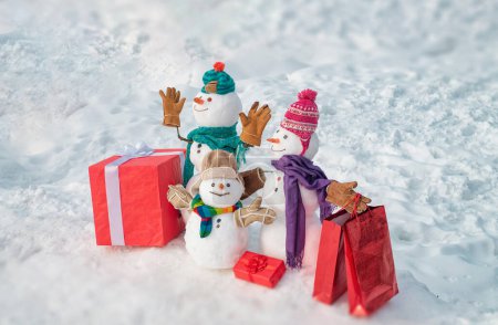 Photo for Delivery gifts. Snowman with gift in Christmas day. Snowman with a bag of gifts. Family Snowman on the background snowflakes. Winter background with snowflakes and snowman. Snowmen Family - Royalty Free Image