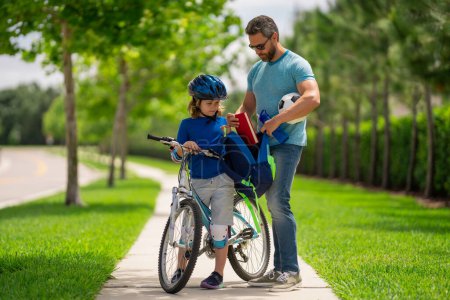 Photo for Father helping son get ready for school. Father teaching son cycling. Father and son learning to ride a bicycle at Fathers day. Father support and helping son. Child care - Royalty Free Image