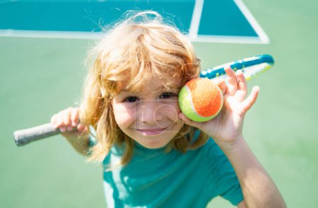 Téléchargez les photos : Enfant jouant au tennis sur le terrain extérieur. Petite fille avec raquette de tennis et ballon dans un club de sport. Exercice actif pour les enfants. Activités estivales pour les enfants. Formation pour les jeunes enfants - en image libre de droit