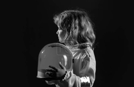 Foto de Retrato de un chico gracioso con casco de astronauta. Lindo niño astronauta niño en traje espacial con casco en el fondo negro - Imagen libre de derechos