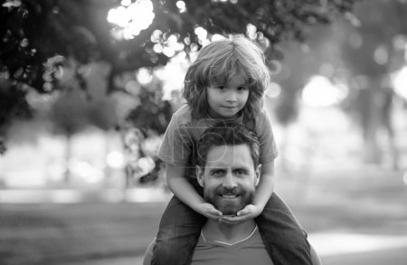 Foto de Padre llevando a su hijo de vuelta al parque. Retrato de un padre feliz dando a su hijo un paseo a cuestas sobre hombros. Lindo niño con papá al aire libre - Imagen libre de derechos