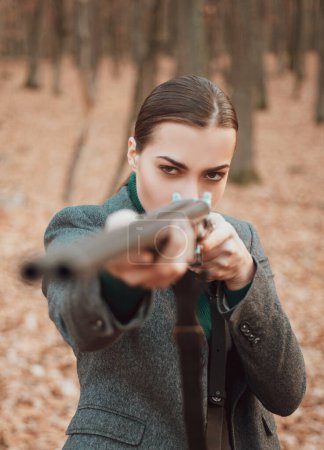 Téléchargez les photos : Femme avec une arme. Un chasseur avec un fusil de chasse et une forme de chasse pour chasser. Femme chasseuse. Chasseur avec un sac à dos et un pistolet de chasse - en image libre de droit