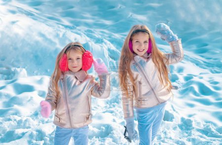 Foto de Feliz invierno. Dos niñitas jugando con nieve en el parque. Retrato de dos niñas jugando con nieve en invierno. Linda hermanas jugando en una nieve - Imagen libre de derechos