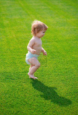 Photo for Warm spring time in the park. Baby in beautiful spring green field. First step - Royalty Free Image