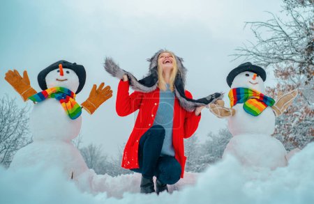 Foto de Tema Navidad invierno año nuevo. Chica feliz invierno haciendo muñeco de nieve. Navidad gente emocionada al aire libre. Niño feliz jugando con un muñeco de nieve en un paseo nevado de invierno - Imagen libre de derechos