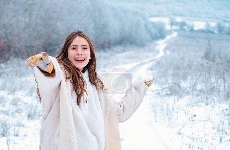 Foto de Mujer feliz invierno sobre fondo nevado. Chica hermosa al aire libre con el pelo largo usando suéter posando en la calle de la ciudad europea. Navidad, concepto de vacaciones de invierno. Nevadas. Copiar espacio - Imagen libre de derechos